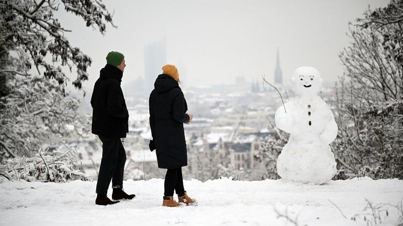 Winteranfang: Glätte und Kälte zum Start in den Dezember Zwei Spaziergänger wandern am Fockeberg (Leipzig) an einem Schneemann vorbei.