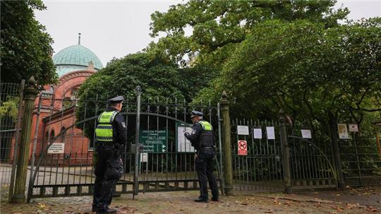 Zwei Streifenbeamte sprechen am jüdischen Friedhof in Hamburg-Ohlsdorf mit einem Friedhofsmitarbeiter.