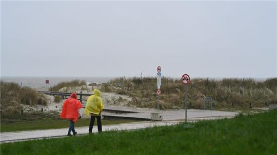 Zwei Tagesgäste laufen bei nassem Wetter in Regenjacken an der Starndpromenade entlang.