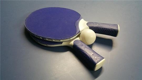 Zwei Tischtennisschläger liegen neben einem Ball.