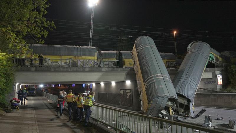 Zwei Waggons eines Güterzugs liegen auf einer Straße in München, nachdem sie von einer Brücke gestürzt sind.