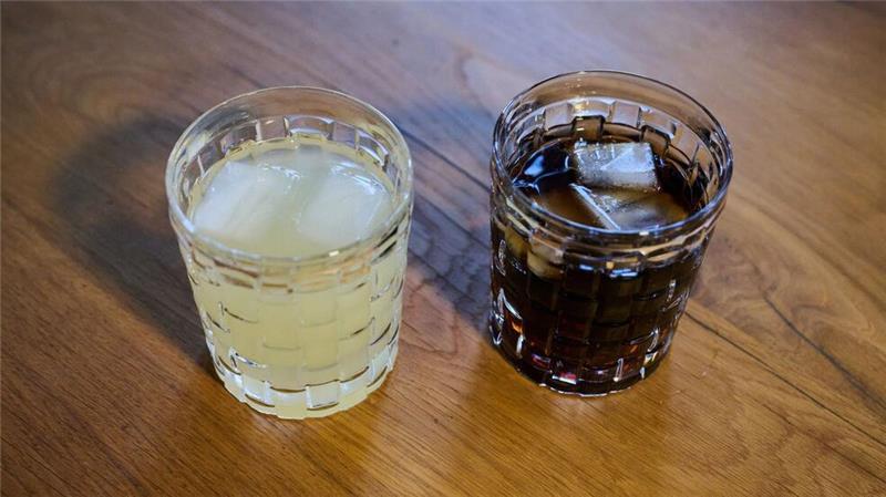 Zwei unterschiedliche Arten Softdrinks mit Eiswürfeln stehen auf einem Tisch