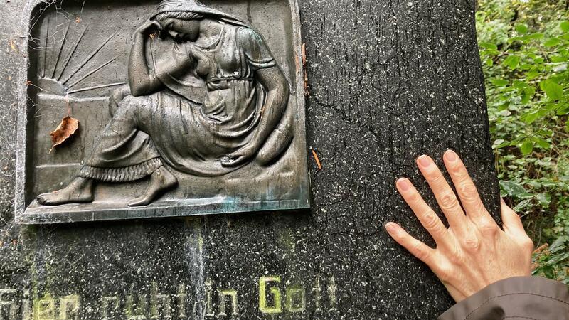 Ein Frau berührt einen Grabstein auf dem Friedhof am Hohenwedel.