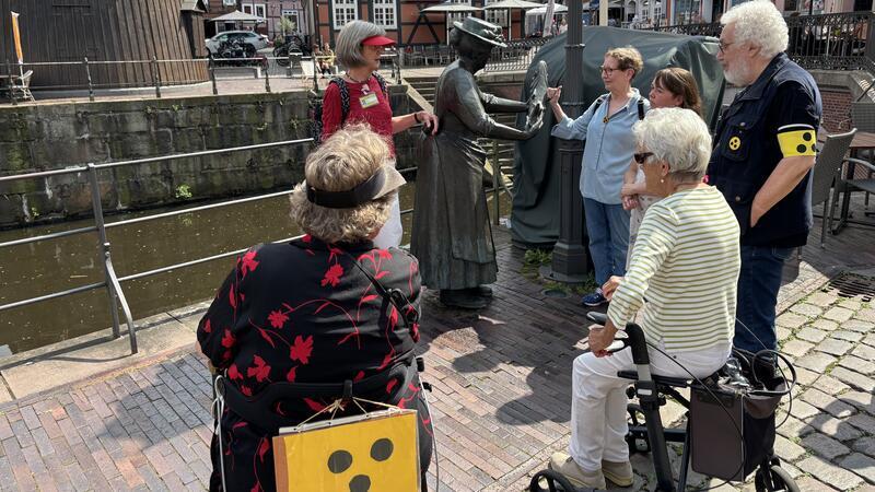 Wie blinde Menschen in Stade auf Sightseeingtour gehen Zwischenstopp bei Mutter Flint am Fischmarkt. Heike Schlehe beschreibt die Figur.