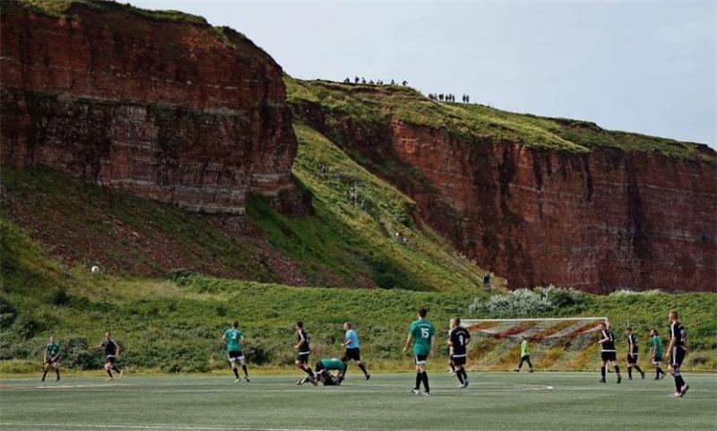 <strong>Fantastische Aussicht: Von einer Felsklippe aus verfolgten zahlreiche Zuschauer das Geschehen auf dem Fußballplatz. Dieser gehört zu Helgolandseinzigem Sportverein, dem VfL Fosite, dessen Mannschaft nach dem Kreisklassenspiel ebenfalls auflief. Foto: Fischer</strong>