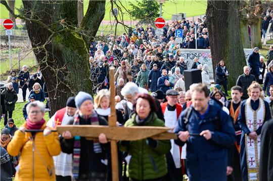 <strong>Gläubige tragen das Holzkreuz vor dem Aufzug. Am Karfreitag zogen zahlreiche Gläubige in Lübeck mit einem Holzkreuz durch die Altstadt und erinnerten auf dem ältesten deutschen Kreuzweg an fünf Stationen an das Leiden und Sterben von Jesus Christus. Foto: Jonas Walzberg/dpa</strong>